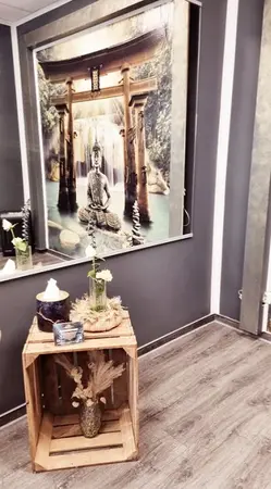 Gemütlicher Spa-Raum mit Buddha-Bild, Dekoration und Holzkiste auf modernem Boden.