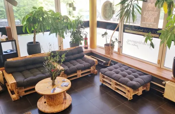 Gemütliche Sitzecke mit Palettenmöbeln, Pflanzen und Couchtisch im modernen Wartebereich.